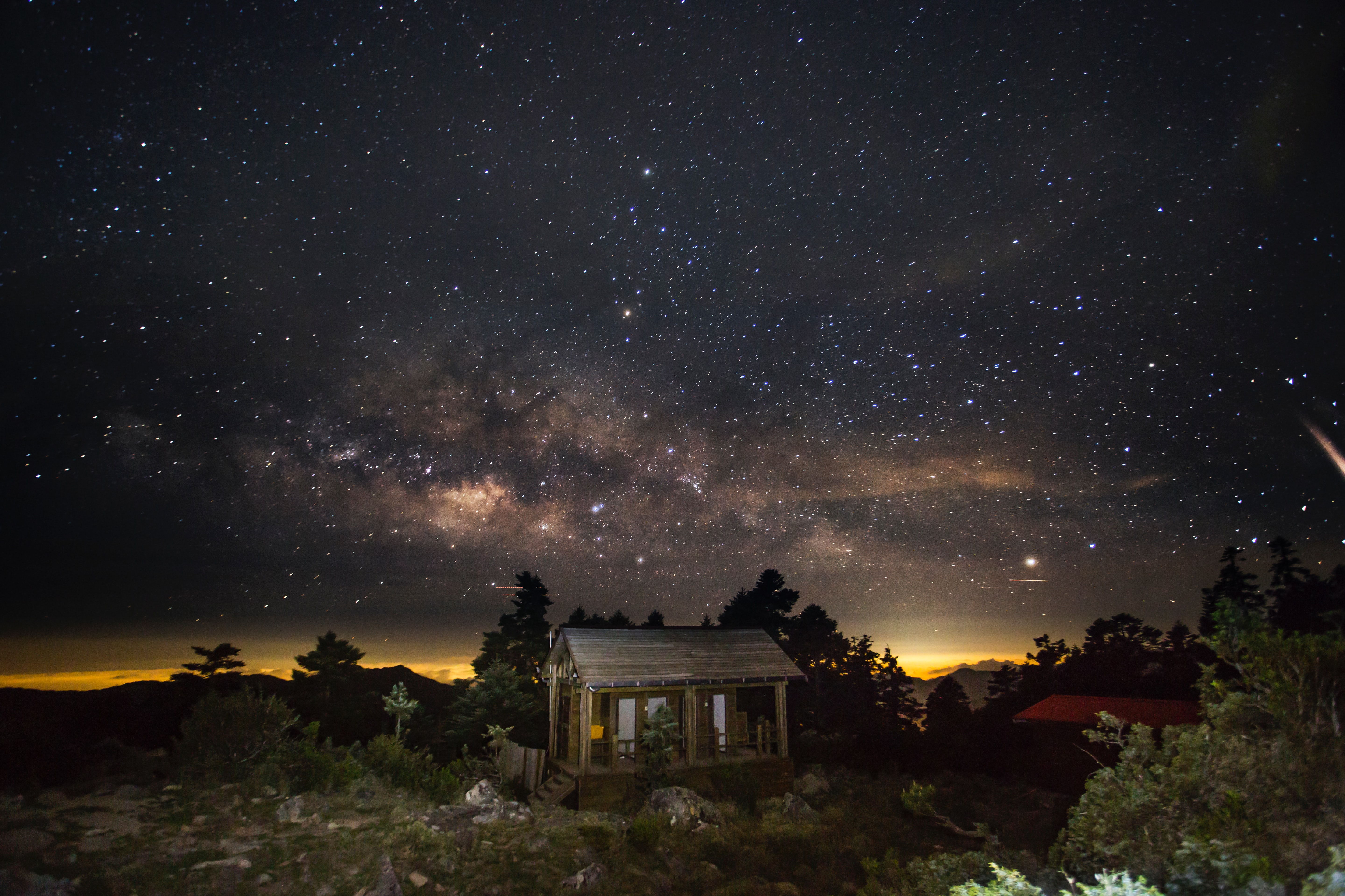 Cabin under a night sky full of stars and the Milky Way.