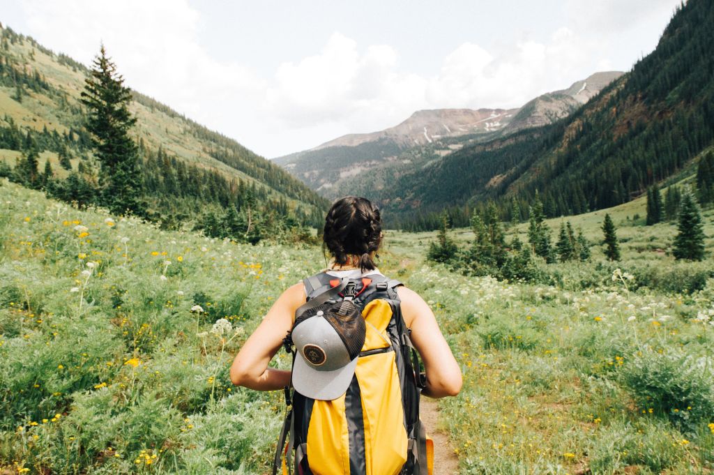 Backpacker walking on a trail in green mountains.